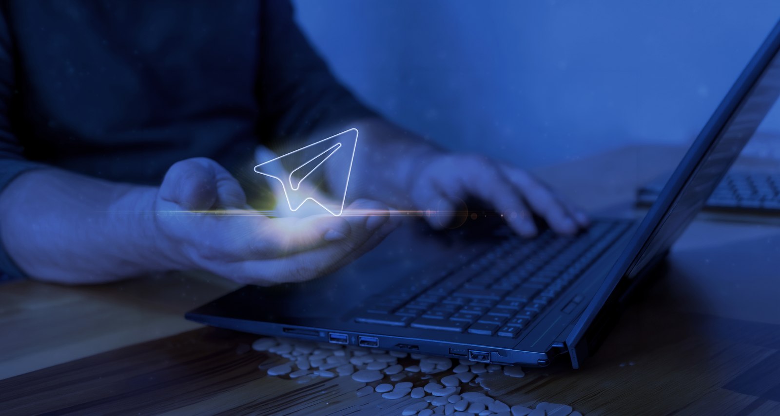 A hand holding a phone with a glowing holographic message icon above a laptop, representing OVEEQ's digital solutions and connected platforms