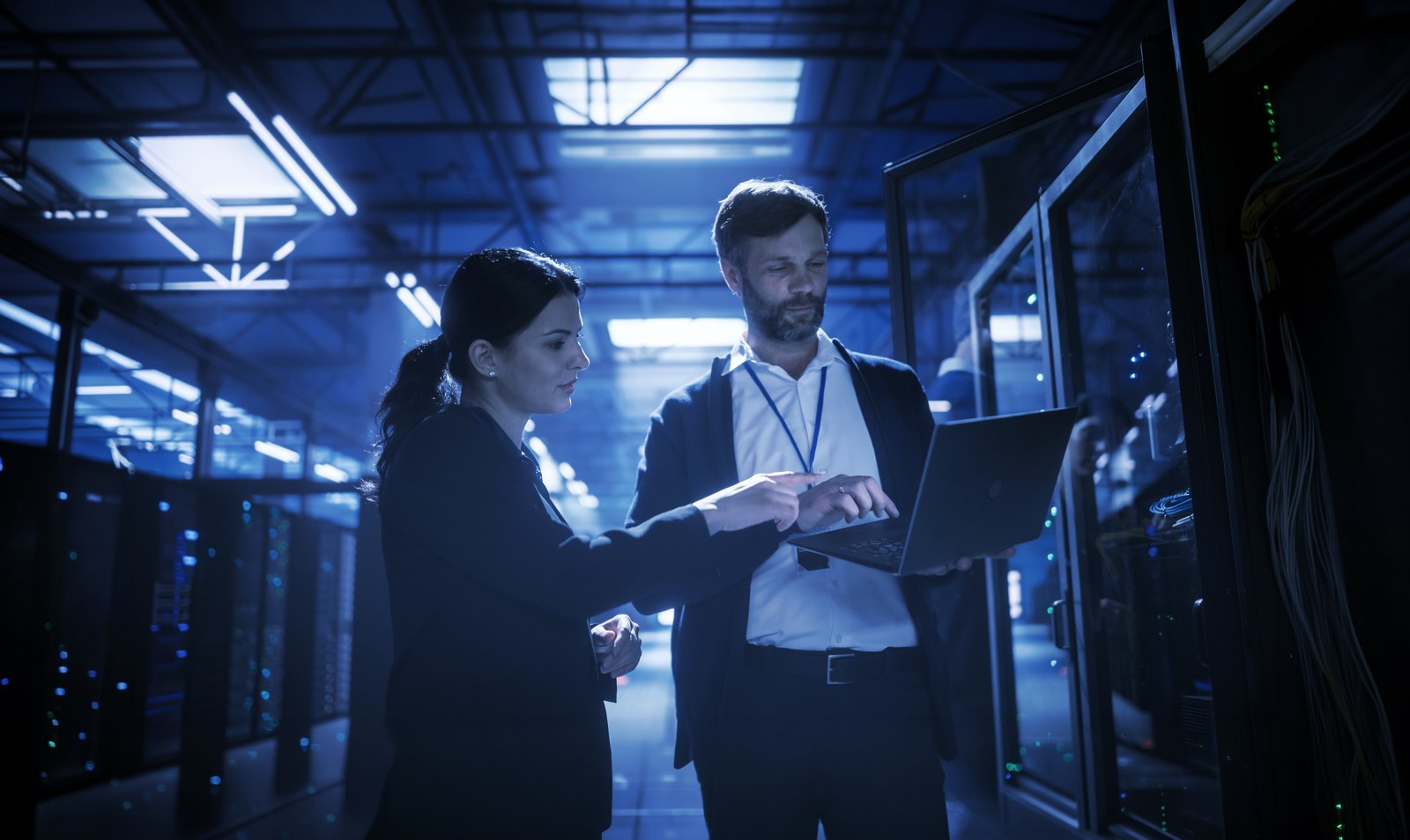 Two OVEEQ professionals reviewing a laptop together in a data centre aisle, representing our hands-on professional services engagements